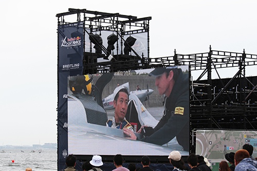 レッドブル・エアレース千葉 Round of 14 勝利を伝えられ安堵の表情を見せた室屋選手が大型スクリーンに映し出される